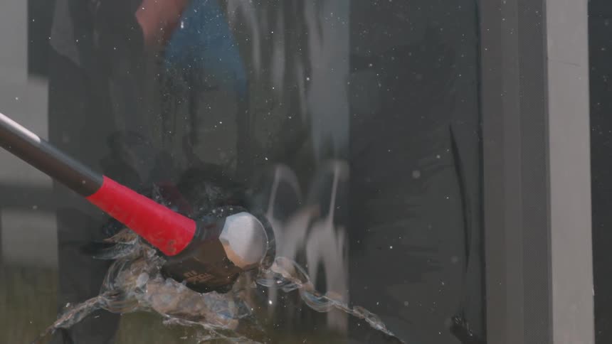 A sledgehammer smashes into glass and slowly falls out