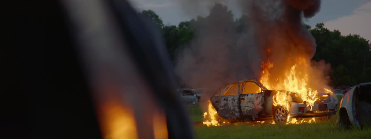 A car burns in a yard at sunset