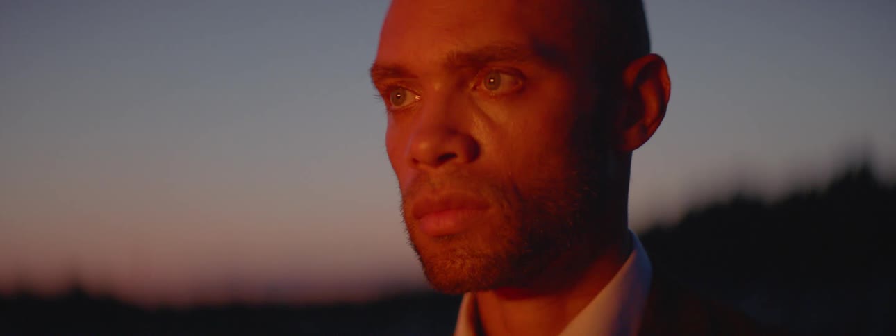 A man staring into the distance where lights are flashing