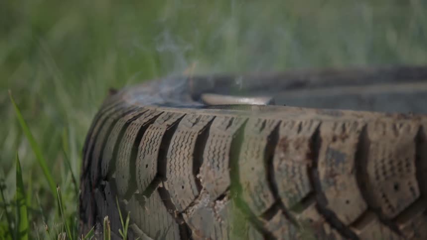 A tire that is on fire in the middle of a grassy field