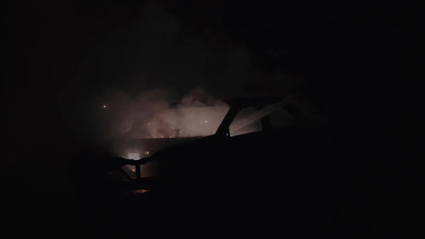 Car blazing on fire smokes and flashes at night