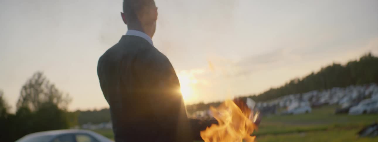 A person that is throwing a bottle that is on fire into a lake