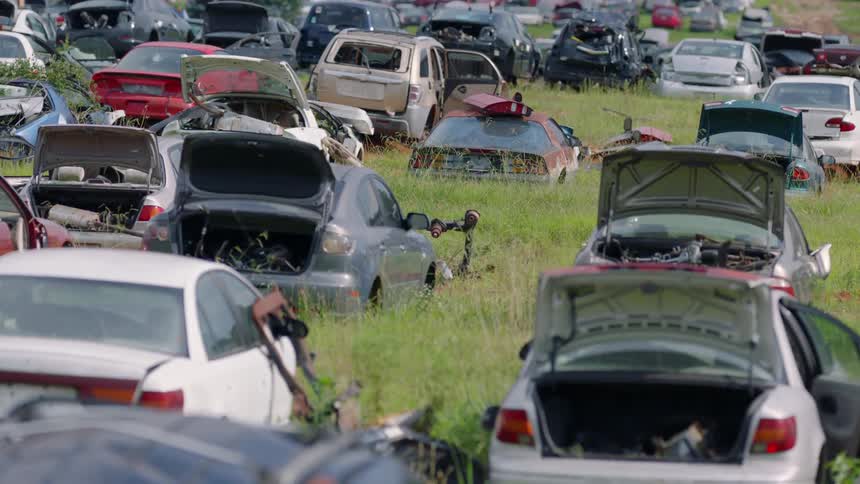 A collection of cars that are broken down in a grassy field