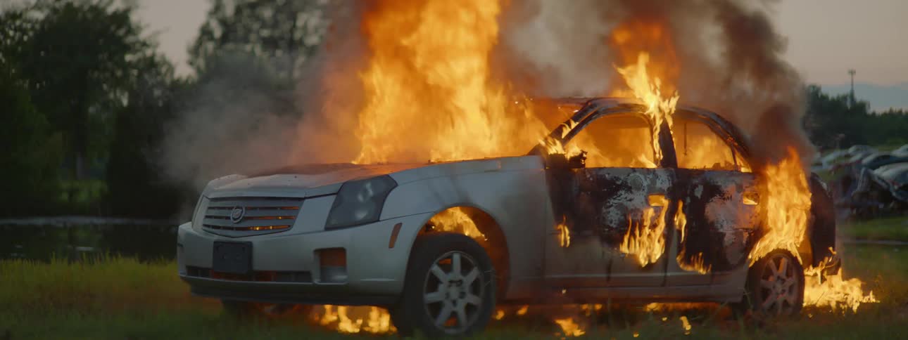 Fire burns a car and smoke fills the air