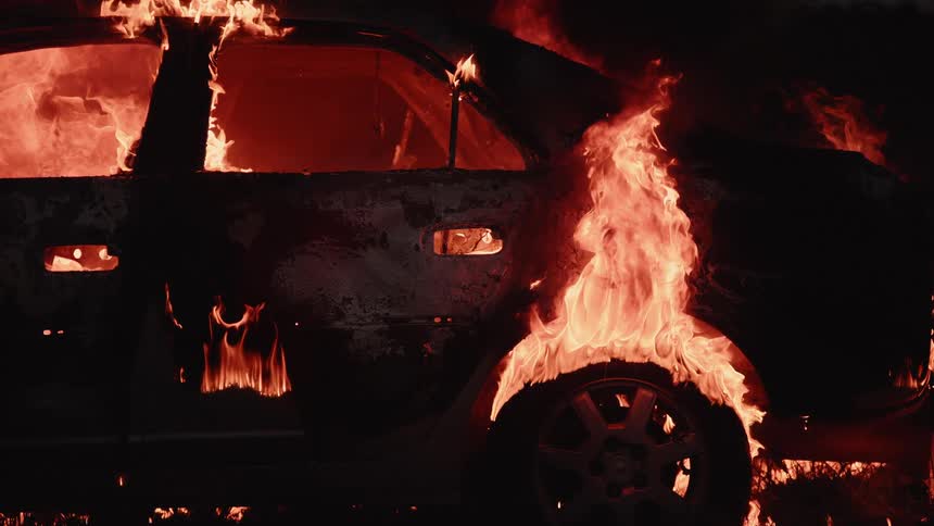 A car is completely on fire and is nearly burnt down to the frame in slow motion