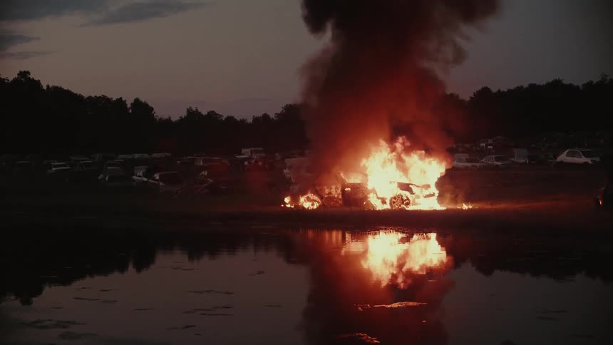 Fire burns in a field at sunset