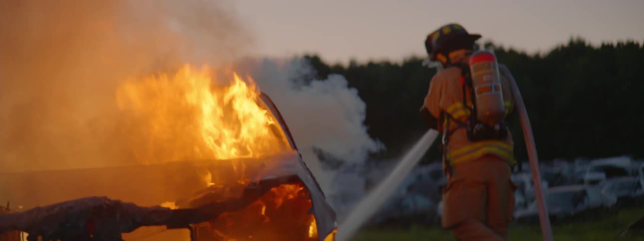 Firefighter extinguishes flames on a burning car