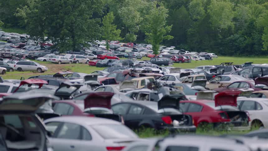 Hundreds of cars parked outside in a field