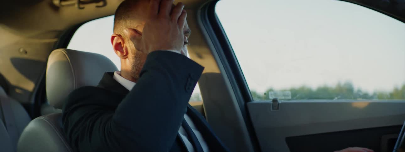 Sleeping man in a vehicle wakes up and rubs his eye