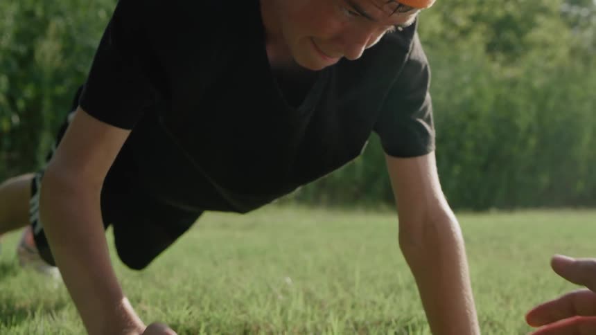 A man doing pushups out in a field with another person