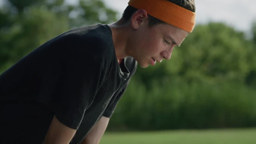 A boy that is breathing heavy with a sweatband on their head