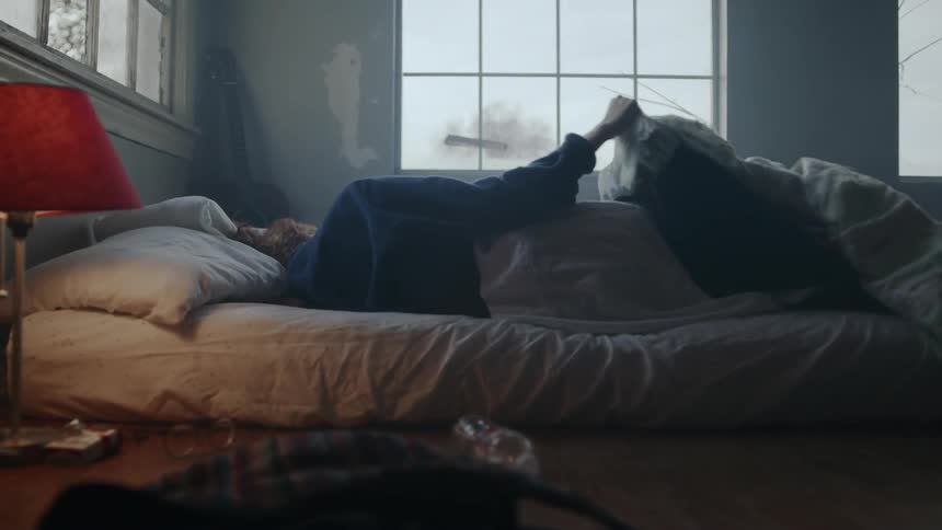 A person is lying in bed and moving blankets