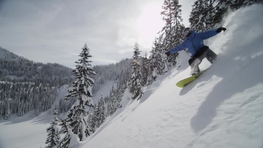 A snowboarder snowboarding down a mountainside