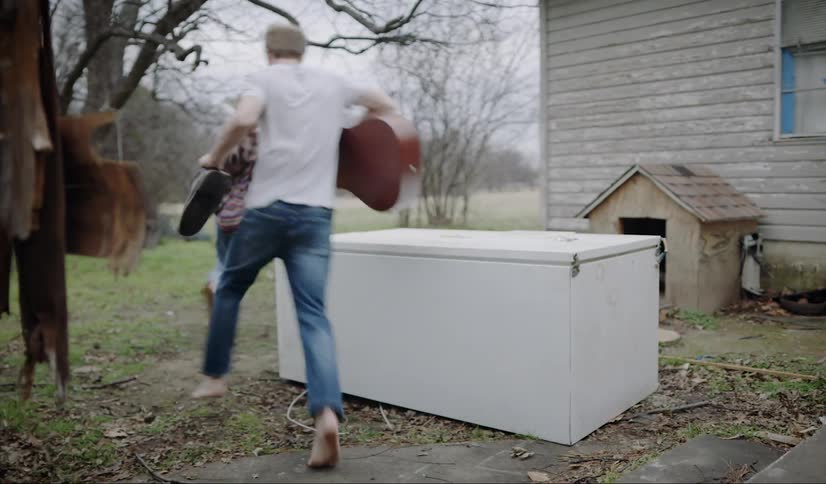 A man and woman run out the door then down stairs and around a house