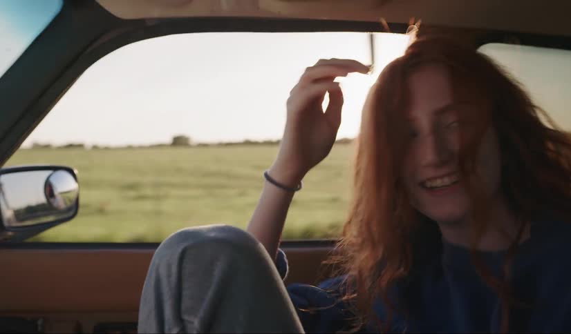 A woman leaning out of a car window driving down a street