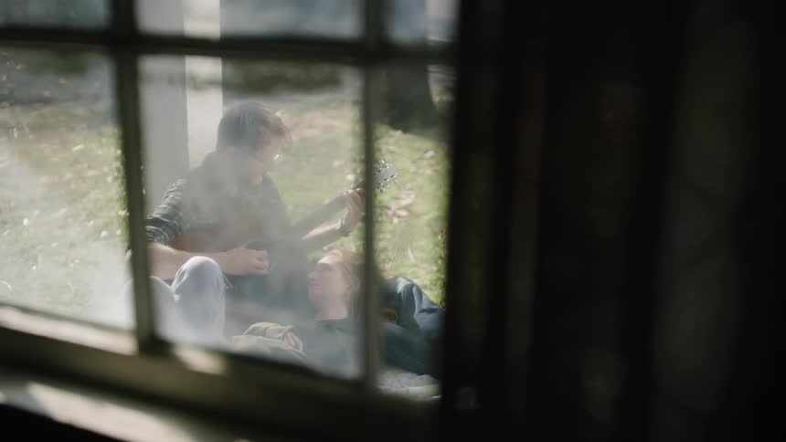Man playing guitar while a woman lays with her head on his lap