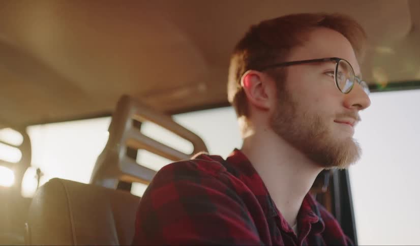A man driving a vehicle with the wind blowing his hair