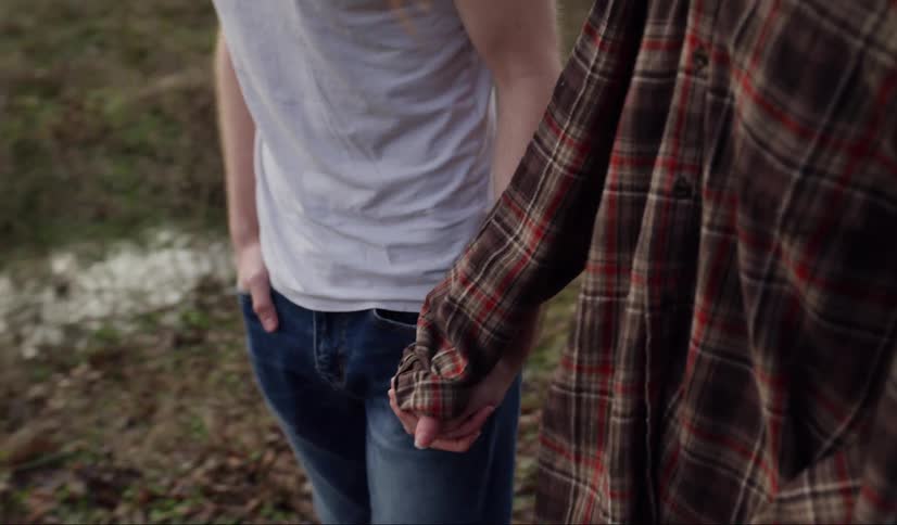 A woman and man are holding hands while walking outside