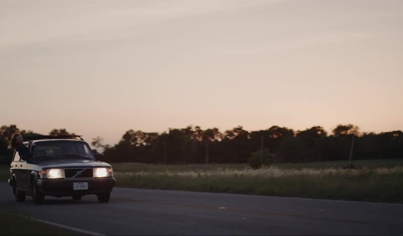 Two cars are driving on the road at dusk