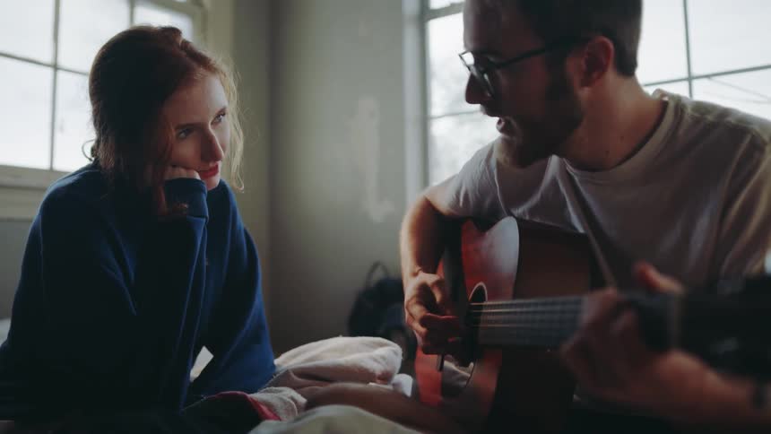 Man plays guitar while woman watches