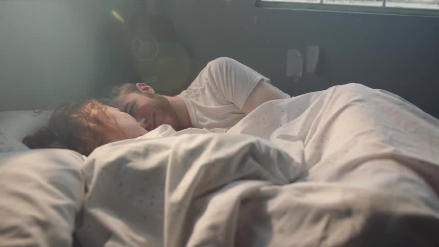 A man and woman are laying in bed together