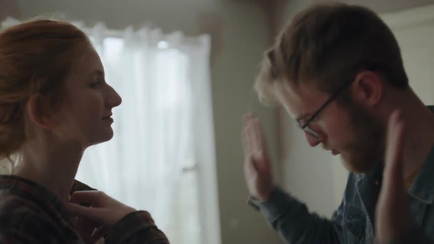 A man and woman standing around in a room talking to each other