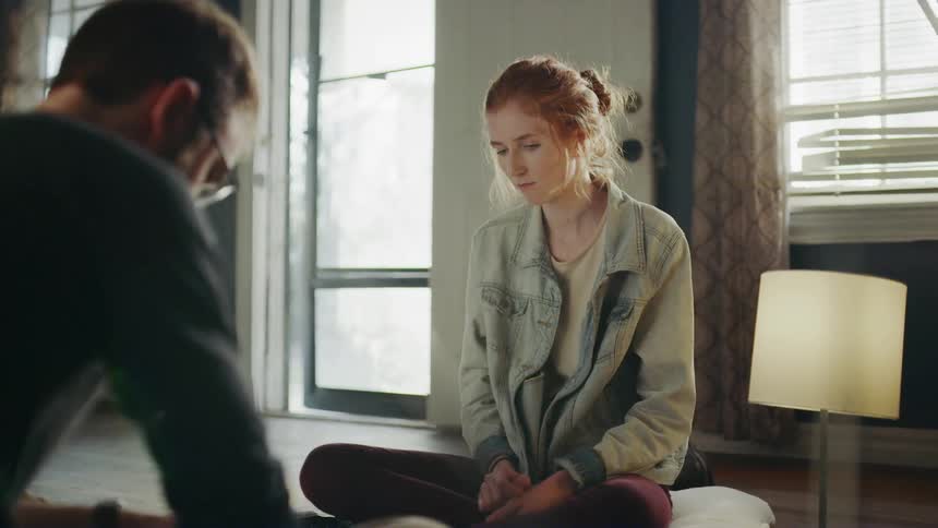Woman sitting on the floor snacking on food across from a man