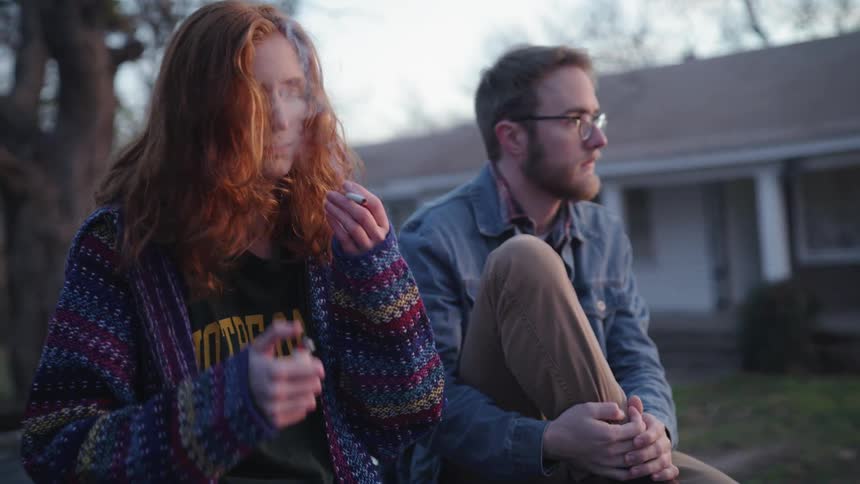 A woman smoking a cigarette next to a man