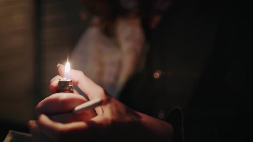 A woman rubs her finger over a lit lighter