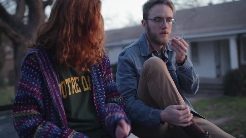 A woman passes a cigarette to a man beside her