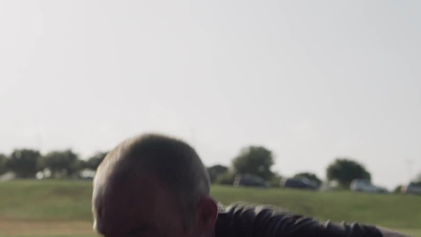 A man doing pushups out in the middle of a grassy field