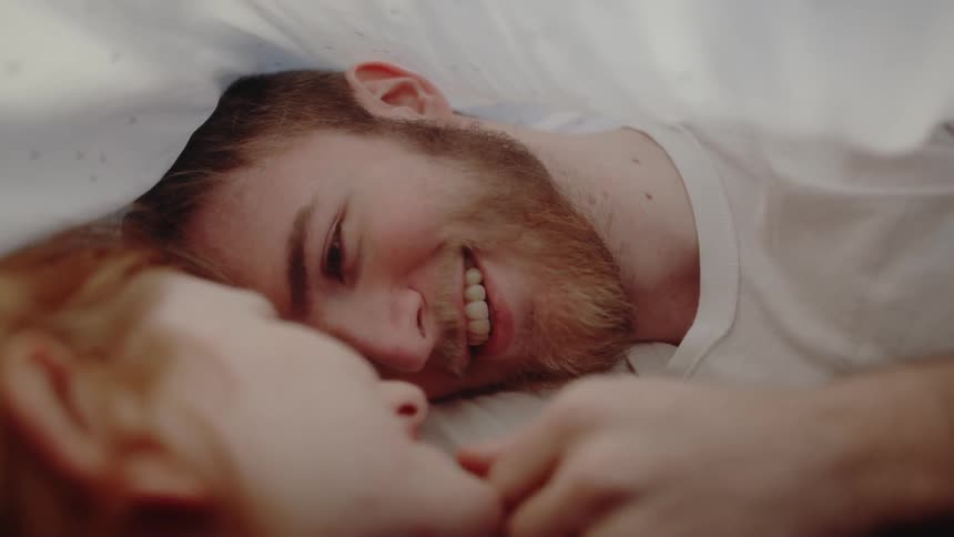 A man and woman cuddling under some blankets