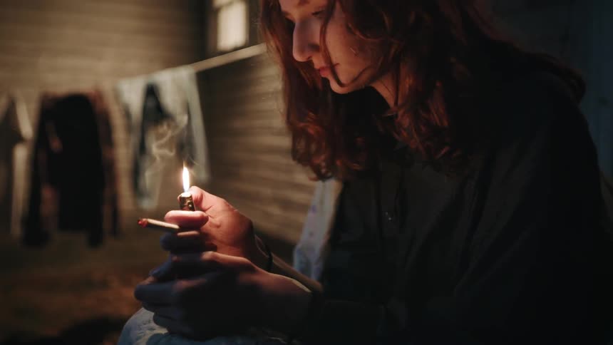 A woman with a lit cigarette is flicking a lighter