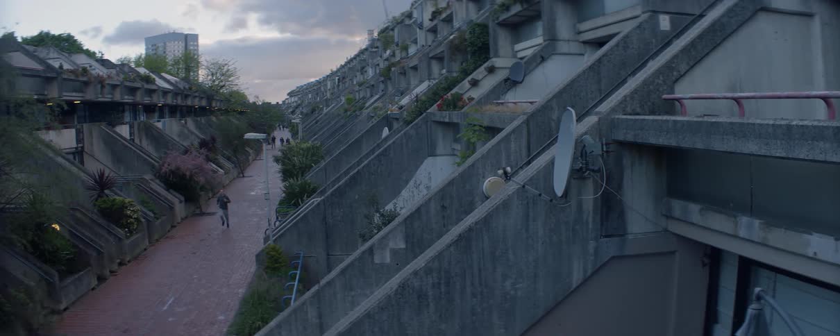 Man jogging down a brick path between a very large row of homes