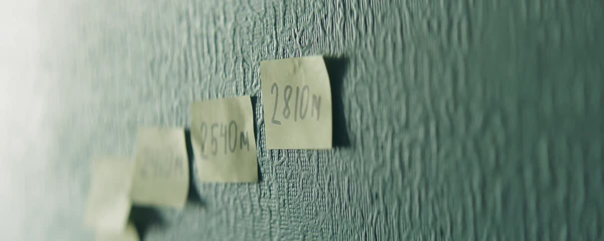 Yellow notes of which are written numbers are placed onto a wall by a human hand