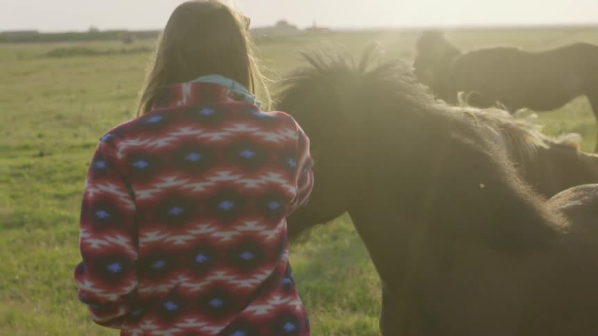 A woman standing near horses in a field