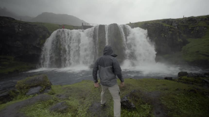 A man walking toward a waterfall