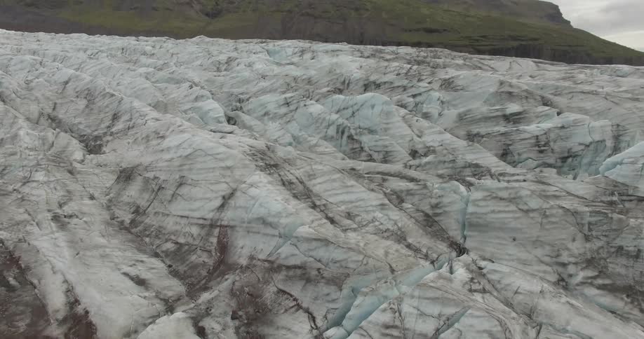 Aerial view of a thick ice sheet covering the hills close to a mountain