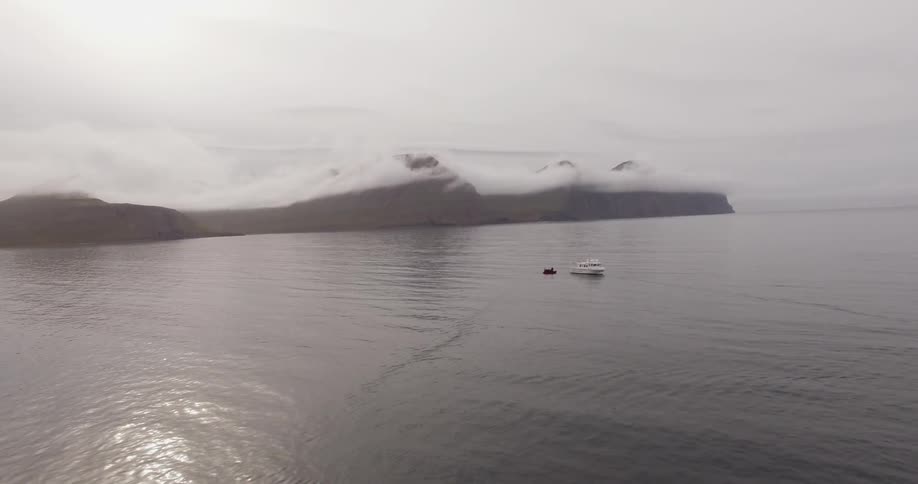 A boat and a dinghy floating in an empty arctic ocean