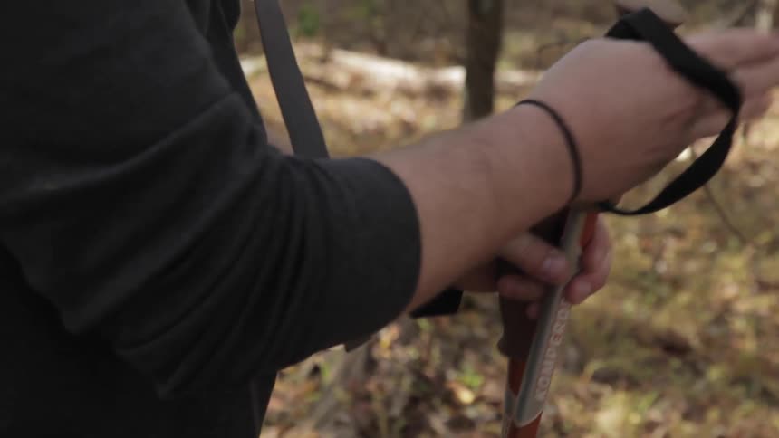 A person adjusts the straps of hiking poles around their wrists