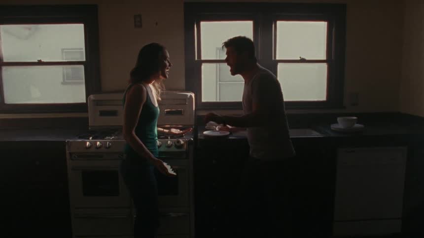 A man and a woman have an argument in front of the kitchen stove and the man breaks a plate