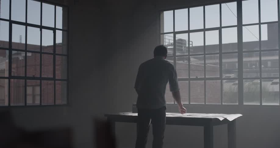 A man is leaning over a desk to write and picks up some papers