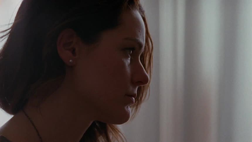 A woman sitting in a room looking sad and pensive