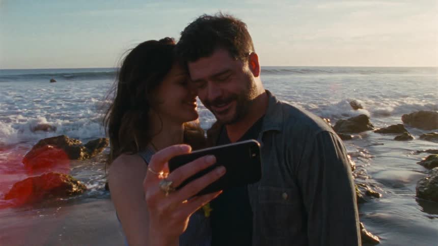 Loving couple taking a selfie on a beach at sunset
