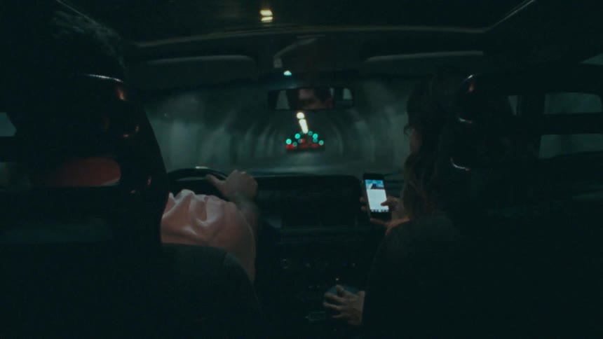 A man and a woman driving a convertible through a tunnel at night