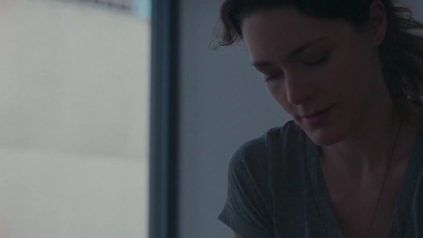 A woman sits by a window and looks through a box