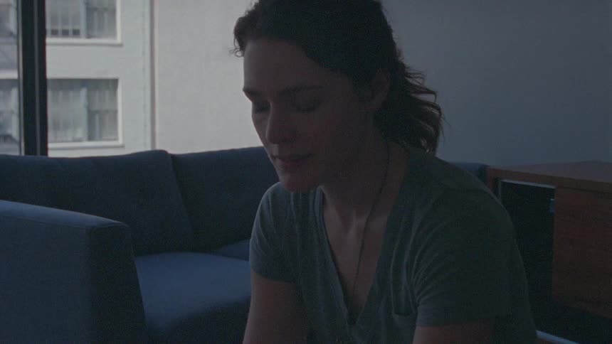 A woman lifts pictures from a moving box and contemplates them