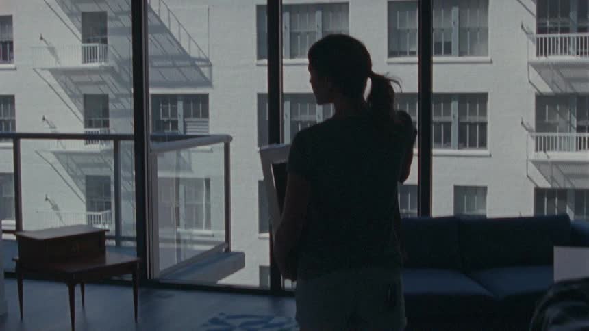 A woman carrying a box in a city apartment
