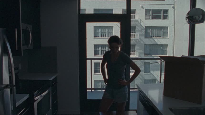 A woman looking in a box in a city apartment