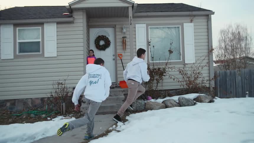 Boys playing football in a snow-covered front yard
